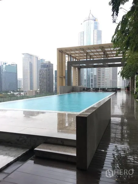 Condominium for rent in Pathum Wan, Bangkok - Infinity-edge swimming pool with shaded deck and city high-rise backdrop.