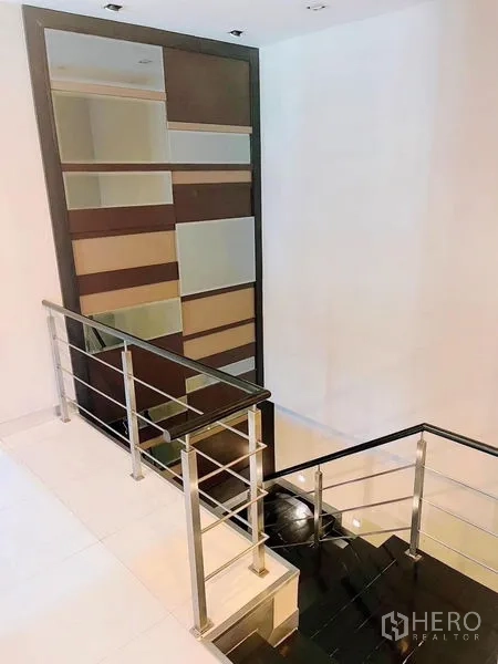 独立式住宅 出租或出售在Prawet, Bangkok - 楼梯间配金属扶手与装饰置物墙，连接上下两层。