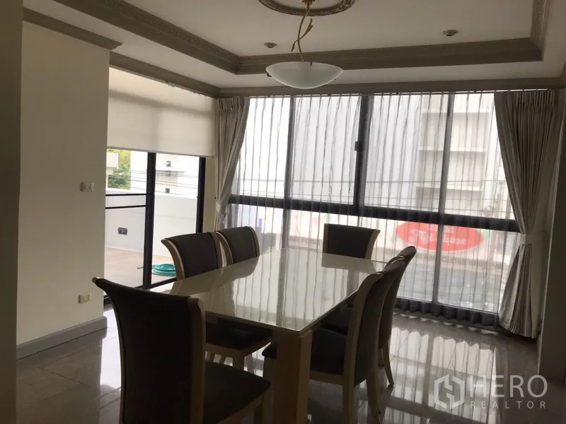 公寓 出租在Watthana, Bangkok - 餐厅区域，六人餐桌，落地大窗与纱帘，旁有阳台出入口。