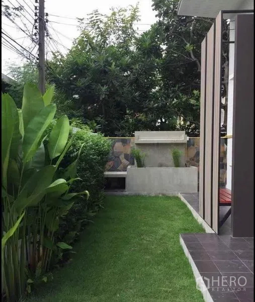 Detached House for rent in Wang Thonglang, Bangkok - Compact front garden with manicured lawn, hedge and a concrete bench beside the house.