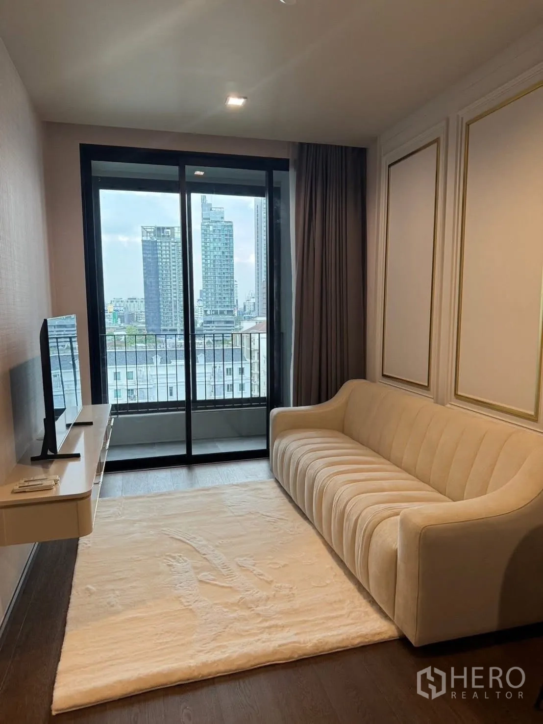 公寓 for rent in Khlong Toei, Bangkok - 客厅配米色沙发、地毯与阳台城市景观。