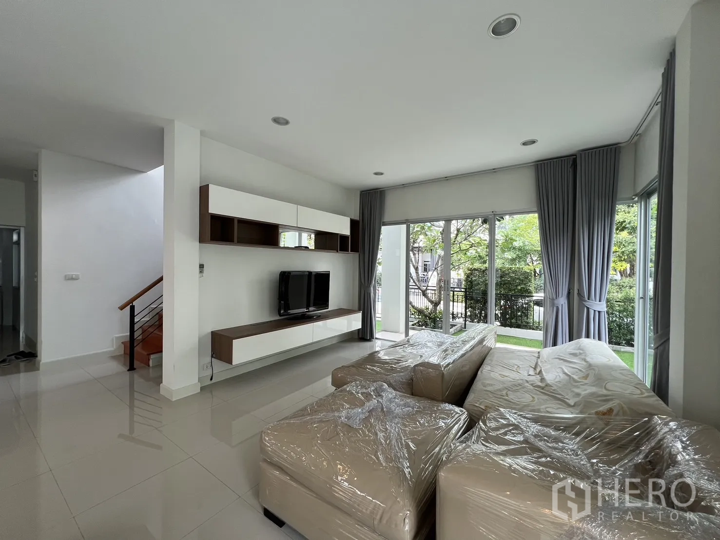 Detached House for rent in Saphan Sung, Bangkok - Living room featuring built‑in TV cabinet and wrapped sectional sofa.