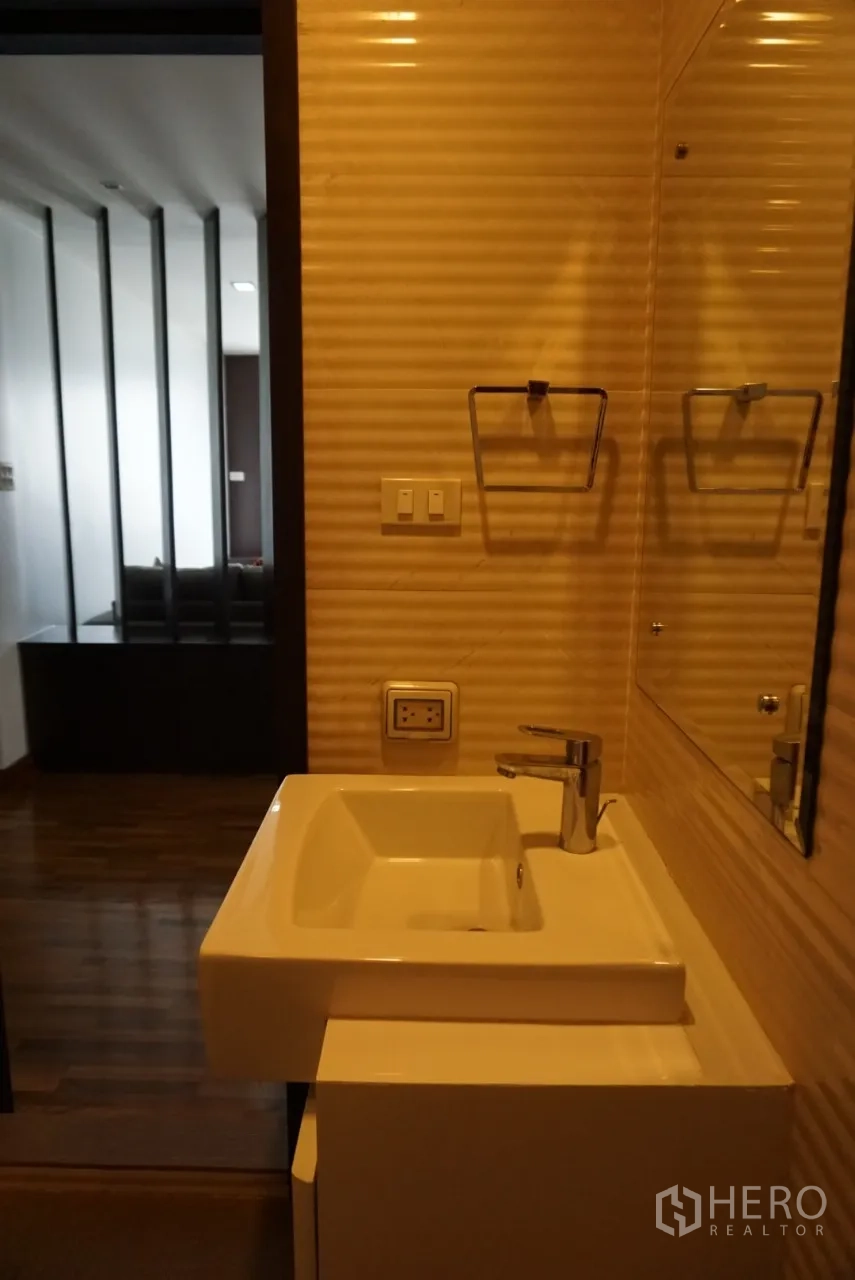 公寓 出租在Watthana, Bangkok - 浴室方形台盆与大镜面，条纹墙面，可见客厅木隔断