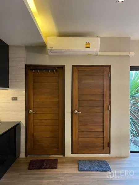 Townhouse for sale in Bang Phli, Samut Prakan - Two wooden interior doors beneath a wall-mounted air conditioner next to the kitchen.