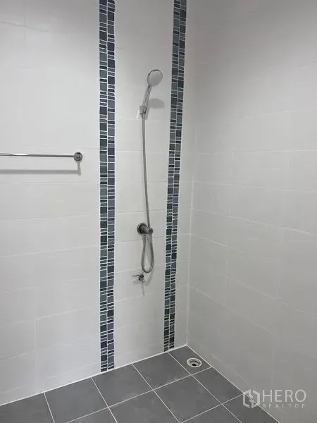 Home Office for sale in Lat Krabang, Bangkok - Minimalist shower with handheld sprayer, white wall tiles and blue mosaic accents.