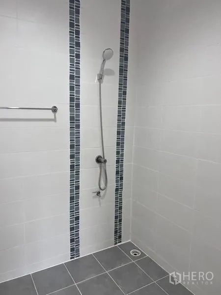 Home Office for sale in Lat Krabang, Bangkok - Minimalist shower with handheld sprayer, white wall tiles and blue mosaic accents.
