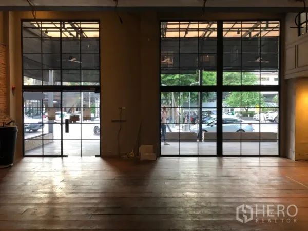 พื้นที่ขายปลีก ให้เช่าในKhlong Toei, Bangkok - ภายในร้านโล่งพร้อมกระจกกรอบเหล็กสูงจรดเพดานและพื้นไม้ มองเห็นถนนด้านหน้า