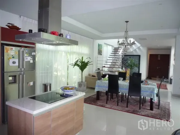 Detached House for rent in Khan Na Yao, Bangkok - Open-plan living and dining area with chandelier, island kitchen and modern staircase