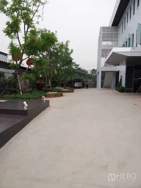 คลังสินค้า ให้เช่าหรือขายในBang Phli, Samut Prakan - ทางเข้าและลานคอนกรีตกว้าง พร้อมพื้นที่จัดสวนข้างอาคารโกดัง