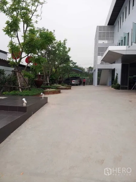 คลังสินค้า ให้เช่าหรือขายในBang Phli, Samut Prakan - ทางเข้าและลานคอนกรีตกว้าง พร้อมพื้นที่จัดสวนข้างอาคารโกดัง