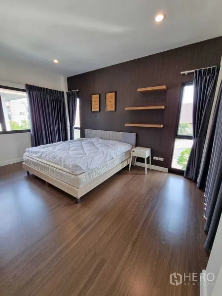 Detached House for rent or sale in Prawet, Bangkok - Corner bedroom with dark feature wall, floating shelves and multiple windows.