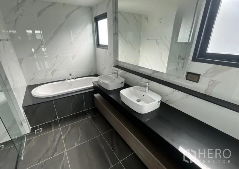 Detached House for rent in Bang Phli, Samut Prakan - Bathroom with double vanity, large mirror, window, and built-in bathtub.