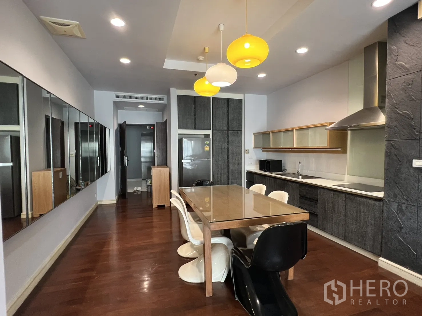 คอนโด for rent in Watthana, Bangkok - ครัวและพื้นที่รับประทานอาหารแบบเปิด พื้นไม้ โต๊ะยาว โคมไฟแขวน ตู้บิลต์อิน และฮูดสแตนเลส