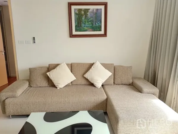 公寓 出租在Sathon, Bangkok - 米色L形沙发配抱枕与现代茶几，墙面装饰画点缀的温馨角落。