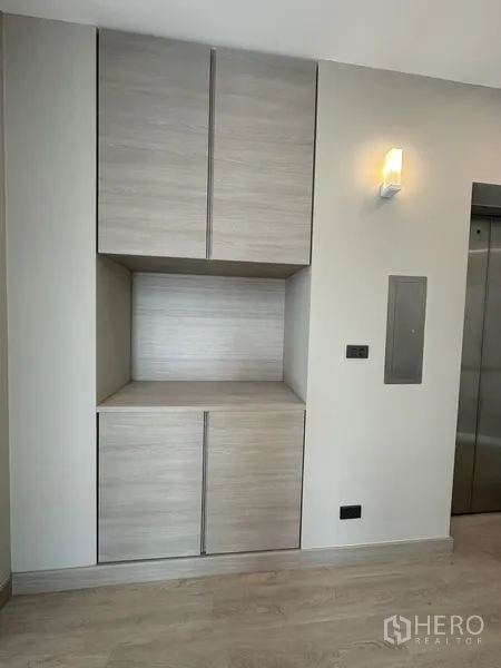 家庭办公室 for rent or sale in Suan Luang, Bangkok - 浅木色嵌入式柜旁的电梯门与墙面灯。