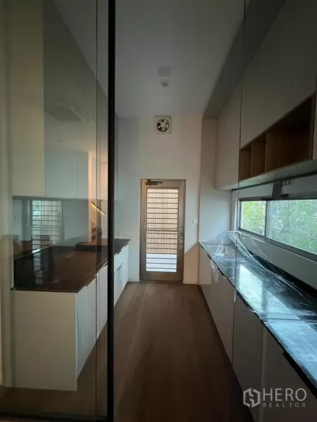 Detached House for rent in Saphan Sung, Bangkok - Enclosed galley kitchen with glass partition, long countertops and a back door to the service area.