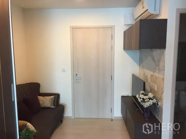 คอนโด ให้เช่าในHuai Khwang, Bangkok - ห้องนั่งเล่นขนาดกะทัดรัด โซฟาสีเข้ม ตู้บิลท์อิน ผนังทีวีลายหินอ่อน พร้อมเครื่องปรับอากาศ