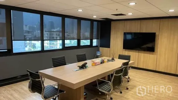Office Space for rent in Khlong Toei, Bangkok - Modern meeting room with a wood conference table, leather chairs, wall-mounted screen and city-view windows in a Bangkok office.