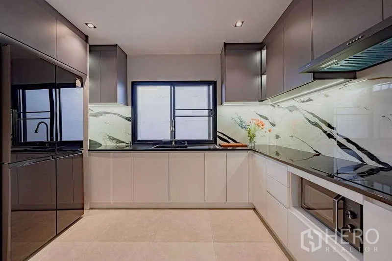 Detached House for rent or sale in Phra Khanong, Bangkok - Sleek Western kitchen with marble-look backsplash, modern appliances, and a window.