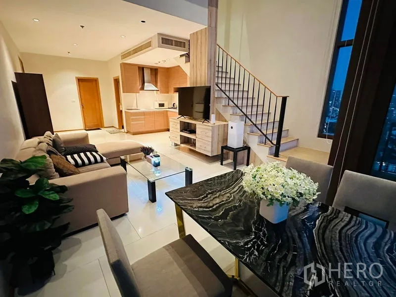 公寓 出租在Bangkok - 从餐区望向厨房与楼梯的复式格局，高挑开阔