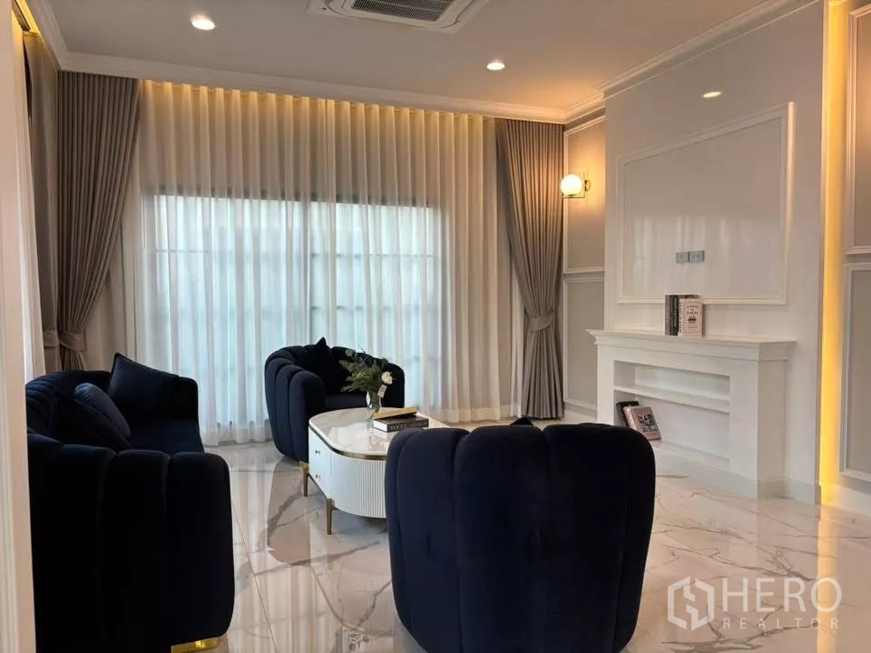 บ้าน ให้เช่าในBang Phli, Samut Prakan - มุมนั่งเล่นอบอุ่น ม่านสูงจรดเพดาน ไฟสวย และบัวผนังคลาสสิก.