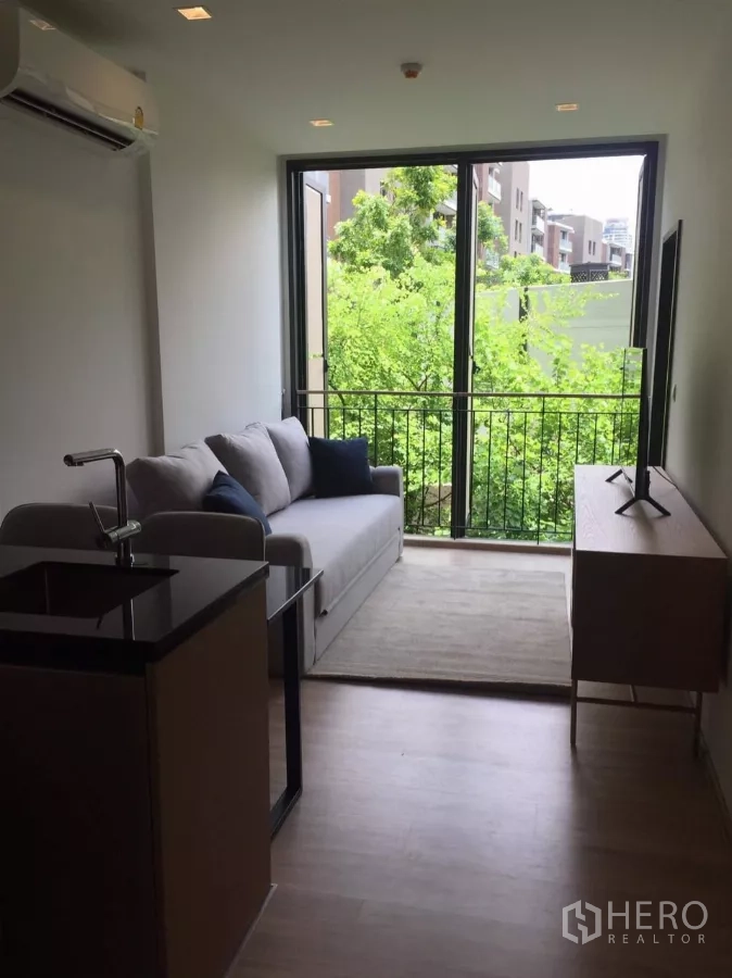 公寓 出租在Watthana, Bangkok - 客厅采光充足，落地窗通向阳台，景观为绿树。