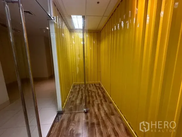 Office Space for rent in Chatuchak, Bangkok - Narrow corridor finished with glossy yellow paneled walls and a frameless glass door.
