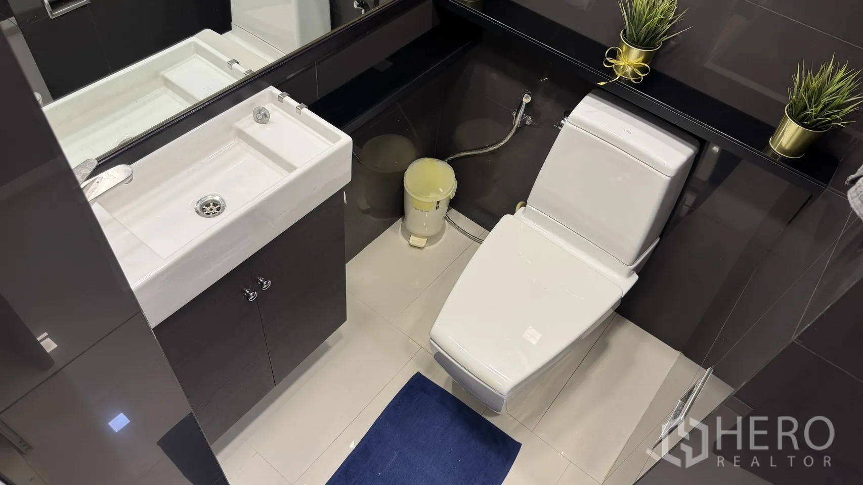 Condominium for rent or sale in Khlong Toei, Bangkok - Compact bathroom with square basin, toilet and black vanity with large mirror.