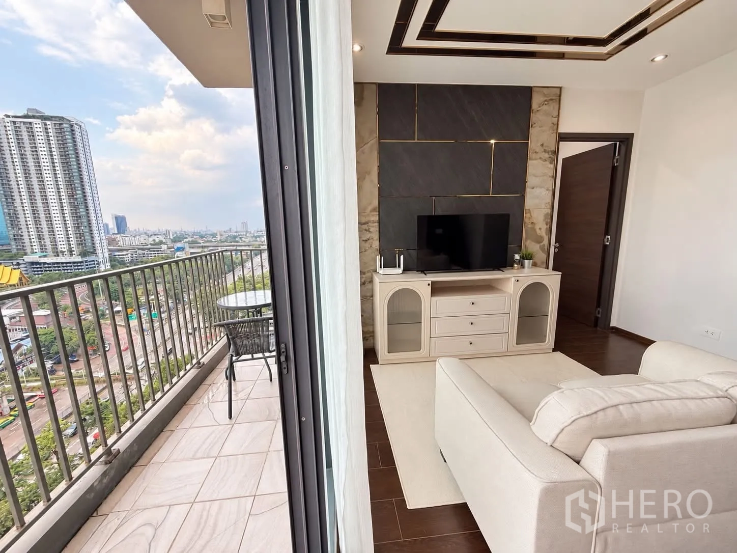Condominium for rent in Watthana, Bangkok - Living room opening to a balcony with outdoor table and sweeping city view.
