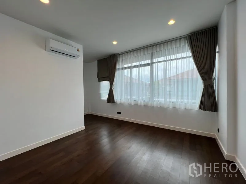 Detached House for rent in Bang Kapi, Bangkok - Spacious bedroom with wide windows, curtains and air conditioning.