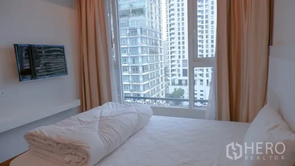 Condominium for rent in Watthana, Bangkok - Cozy bedroom with a large window and city view, featuring a wall-mounted TV.