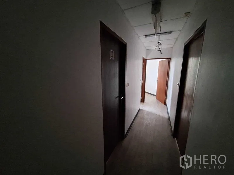 办公空间 出租在Watthana, Bangkok - 昏暗走廊，多扇木门通往独立房间。