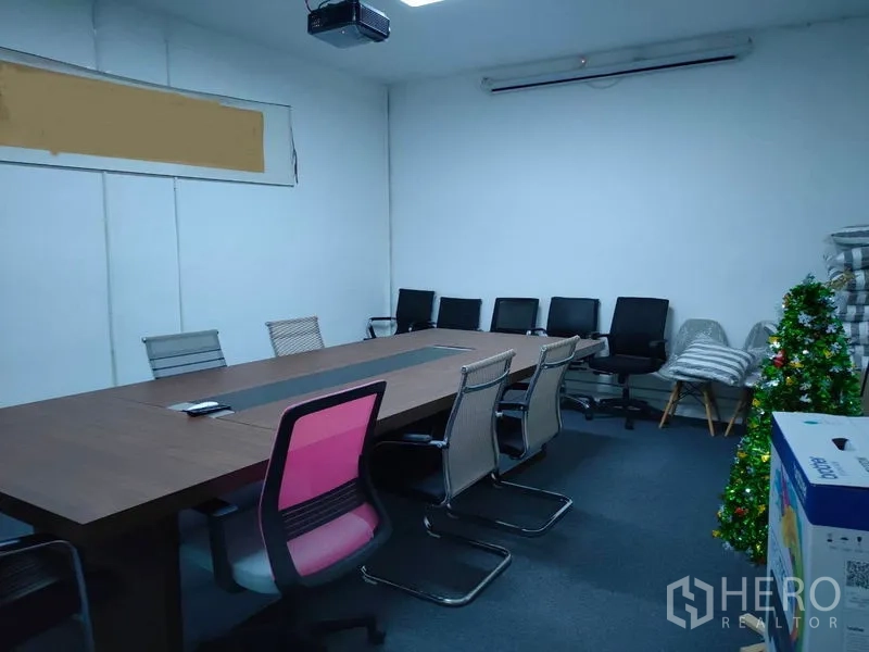 คลังสินค้า ให้เช่าในBang Kapi, Bangkok - ห้องประชุมพร้อมโต๊ะยาว เก้าอี้หลายตัว และเครื่องโปรเจ็กเตอร์ติดเพดาน.