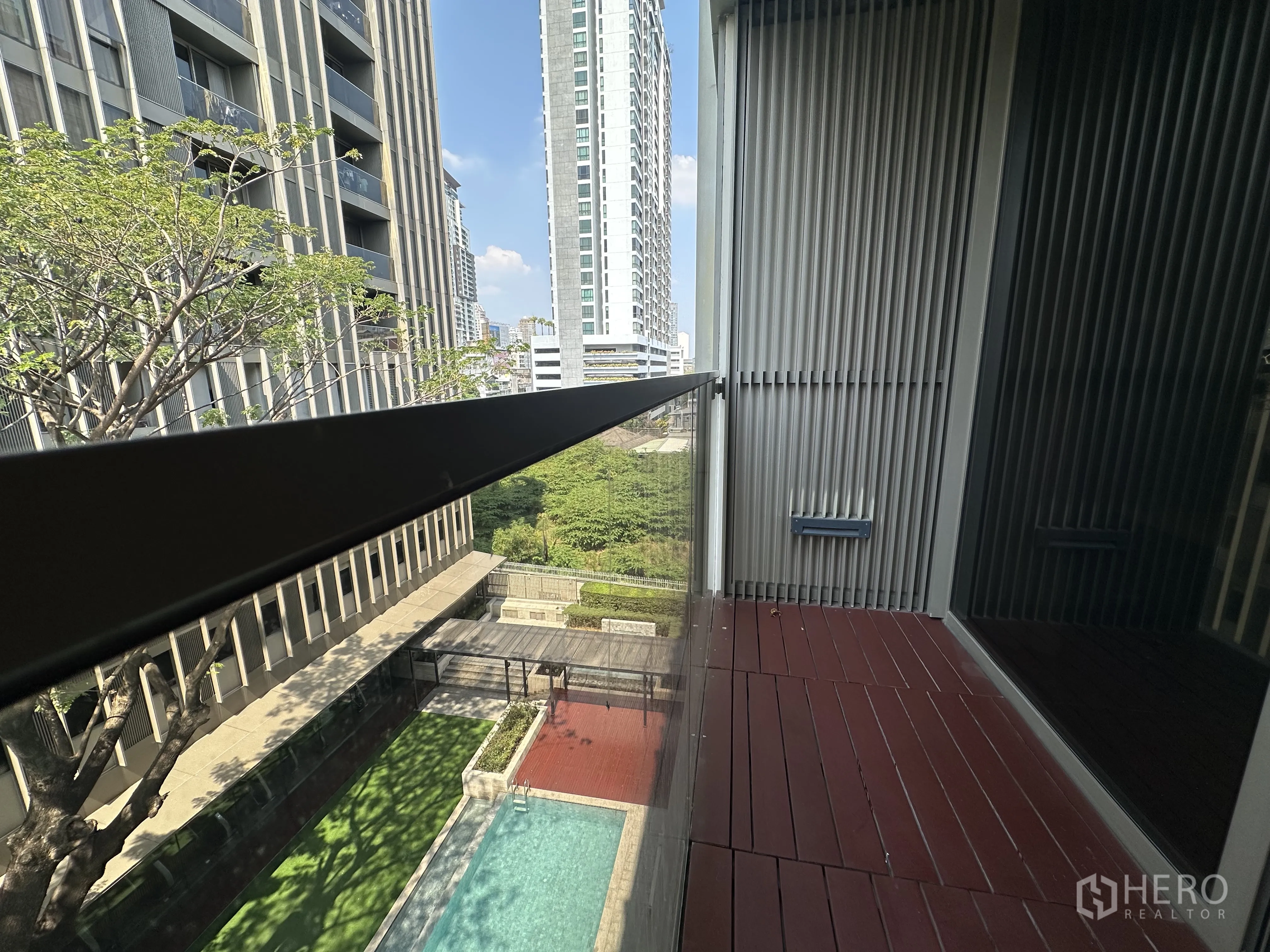 Condominium for rent in Khlong Toei, Bangkok - Private balcony with glass railing overlooking the pool and nearby towers.