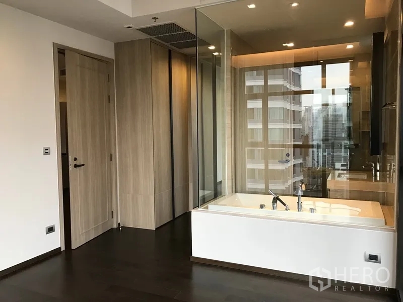 公寓 出租或出售在Watthana, Bangkok - 主卧配玻璃分隔浴缸、内置衣柜与城市天际线景观。