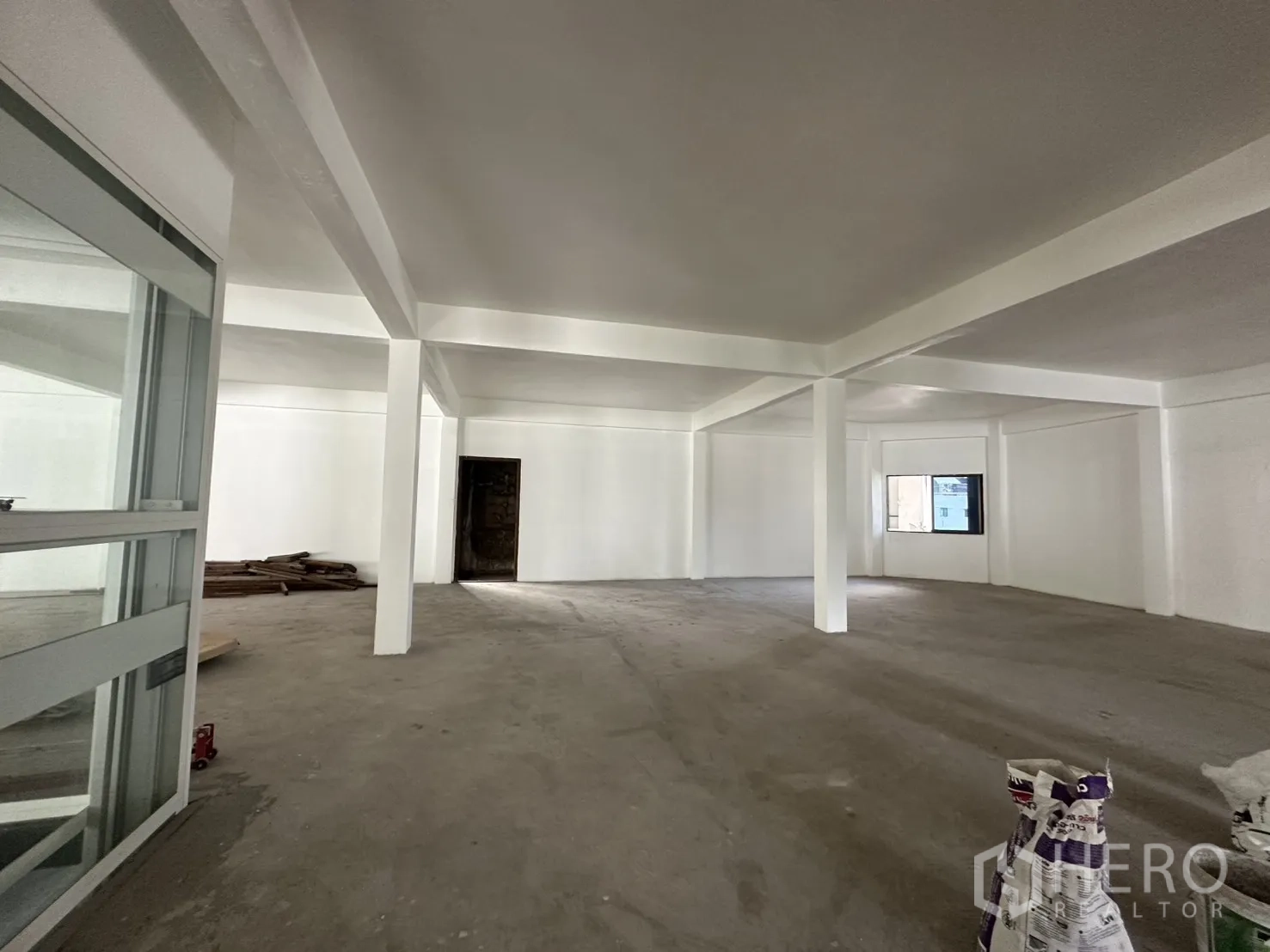 Retail Space for rent in Watthana, Bangkok - Spacious white retail hall with multiple columns, a window, and a doorway, ready for fit-out.