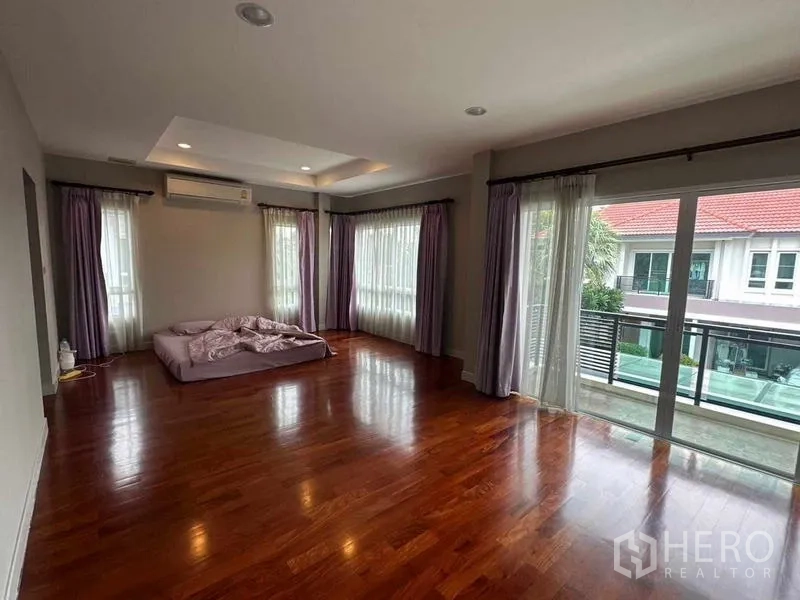 独立式住宅 出售在Saphan Sung, Bangkok - 主卧面积宽阔，实木地板，连通阳台与多面窗帘。