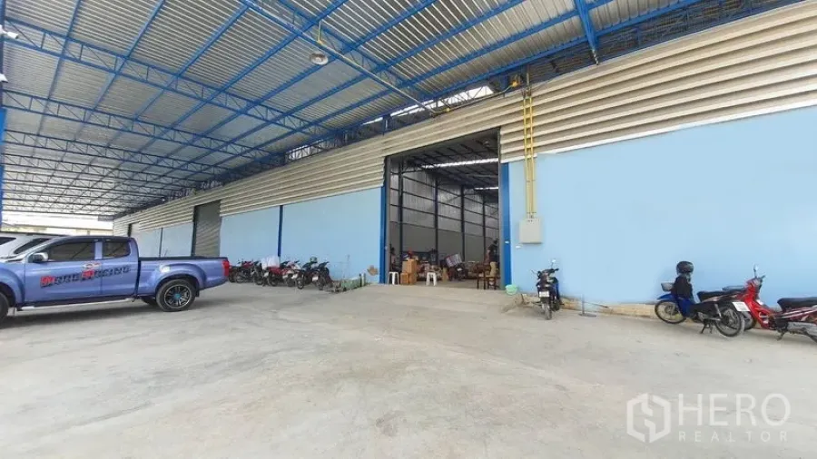 คลังสินค้า ให้เช่าในBang Kruai, Nonthaburi - อาคารโกดังสีฟ้าพร้อมประตูบานใหญ่ ลานโหลดมีหลังคา และพื้นที่จอดรถ