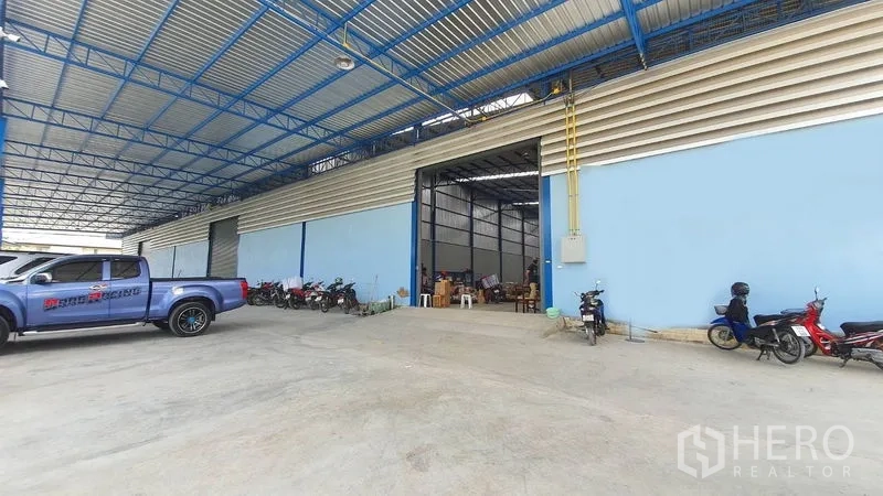 คลังสินค้า ให้เช่าในBang Kruai, Nonthaburi - อาคารโกดังสีฟ้าพร้อมประตูบานใหญ่ ลานโหลดมีหลังคา และพื้นที่จอดรถ