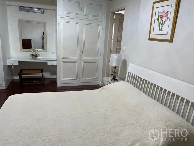 Apartment for rent in Watthana, Bangkok - Cozy bedroom with built-in wardrobe, dressing table and a queen bed.