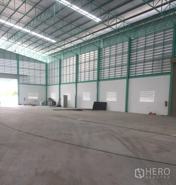 货栈 出租在Samut Prakan - 现代仓库内角度，墙体高挑，配服务门、通风百叶与开阔装卸区。