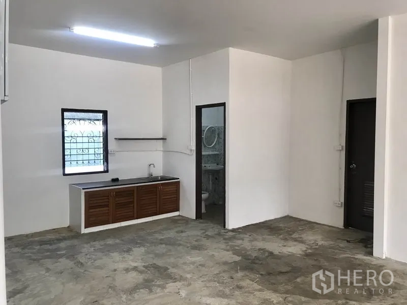 货栈 出租在Pathum Thani - 一层作业区，带内置水槽与厨房台面，旁有卫生间入口。