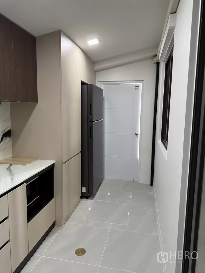 Townhouse for rent or sale in Bang Phli, Samut Prakan - Galley kitchen view with refrigerator and a door to the service area.