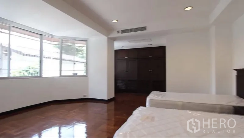 房间 出租在Khlong Toei, Bangkok - 转角大卧室，双床、飘窗与嵌入式衣柜。
