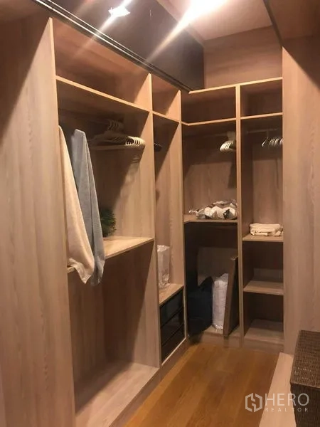 Detached House for rent or sale in Bang Kapi, Bangkok - Walk-in closet with built-in wooden shelves and hanging rails.