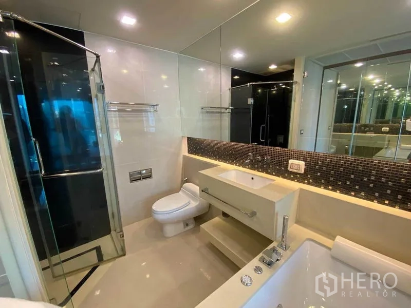 Condominium for rent in Bang Rak, Bangkok - Contemporary bathroom with glass shower, vanity and whirlpool tub.