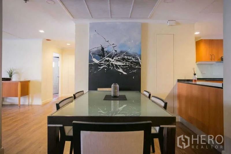 Condominium for rent or sale in Watthana, Bangkok - Dining area with glass-top table and abstract feature wall art.