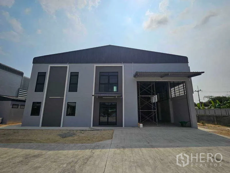 货栈 出租在Mueang Rayong, Rayong - 仓库正立面，带雨棚装卸区与前方停车空地。