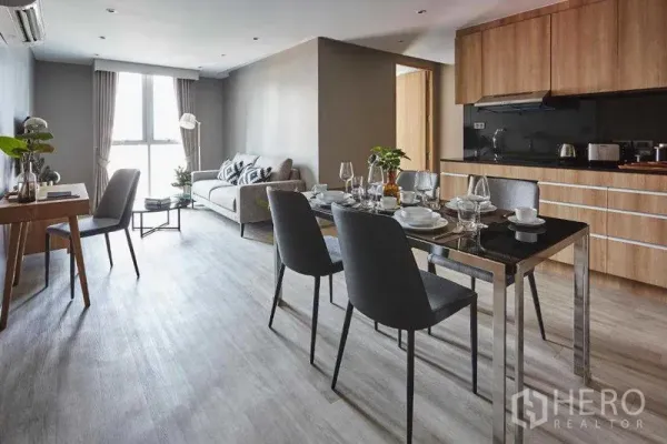 Apartment for rent in Khlong Toei, Bangkok - Open-plan living, dining and kitchenette with wood cabinets and a four-seat dining table
