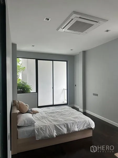 Detached House for rent in Saphan Sung, Bangkok - Bright bedroom with sliding glass doors to a small balcony and greenery.